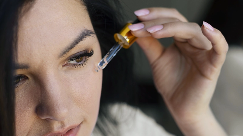 photo of a mature woman applying essential oil on his face