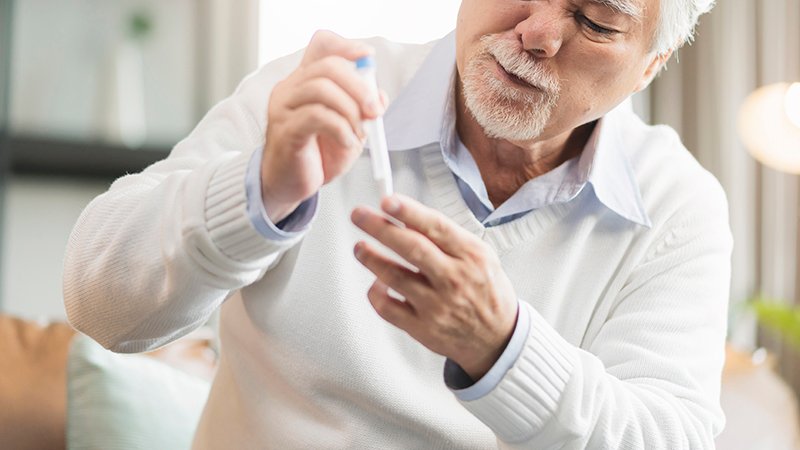 photo of a old man doing a finger-prick test by himself