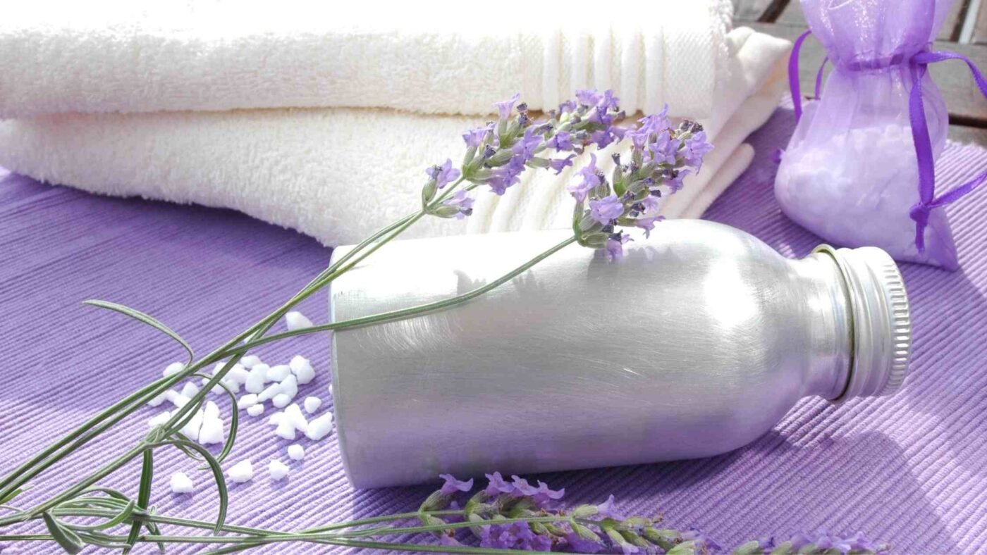 The image depicts a spa-like setting with a metal bottle of colloidal silver, lavender flowers, white towels, and a lavender sachet