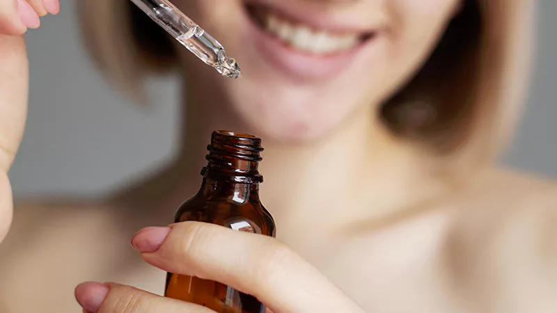 photo of a smiley woman holding essential oils