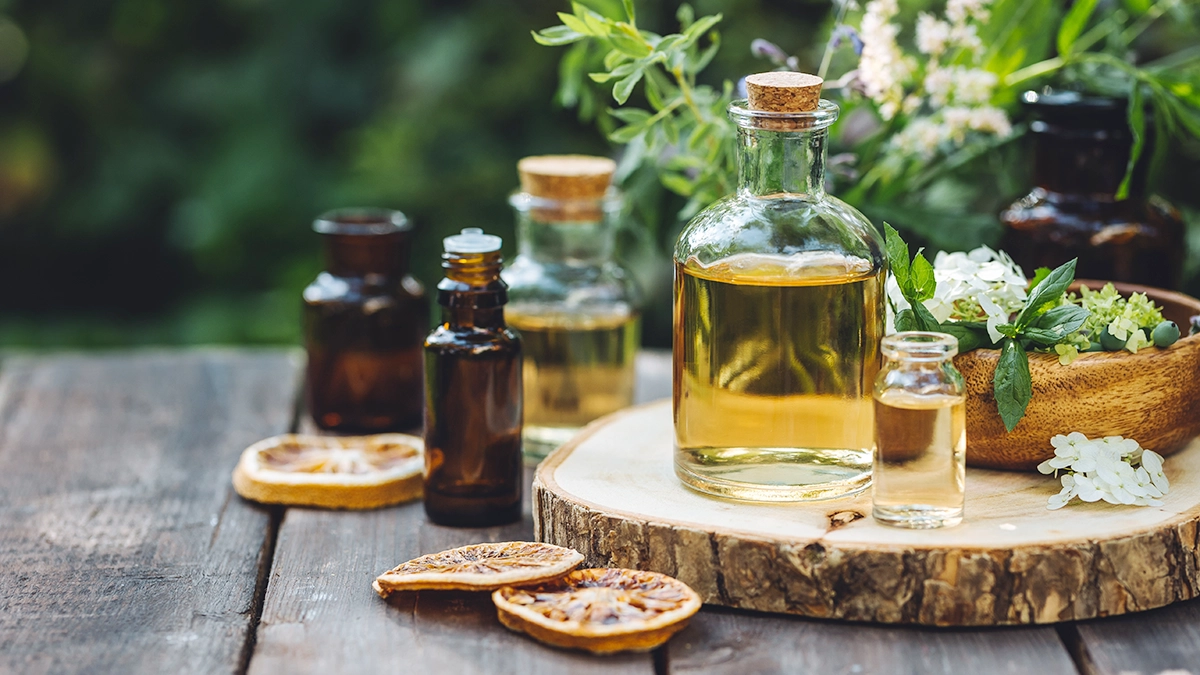 Bottles of essential oils and carrier oils with blending tools on a wooden surface
