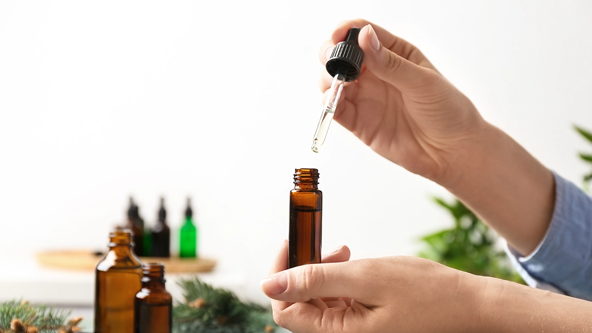 hands blending different essential oils in bottles