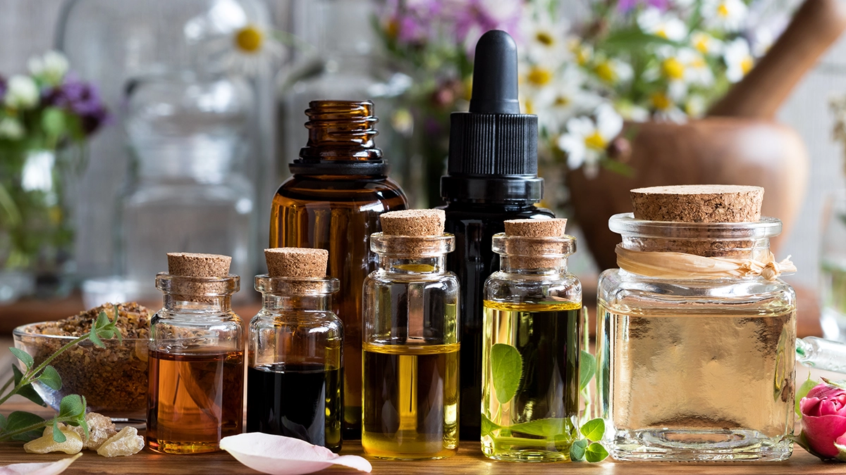 Various bottles of essential oils with flowers and herbs, ideal for clearing sinuses